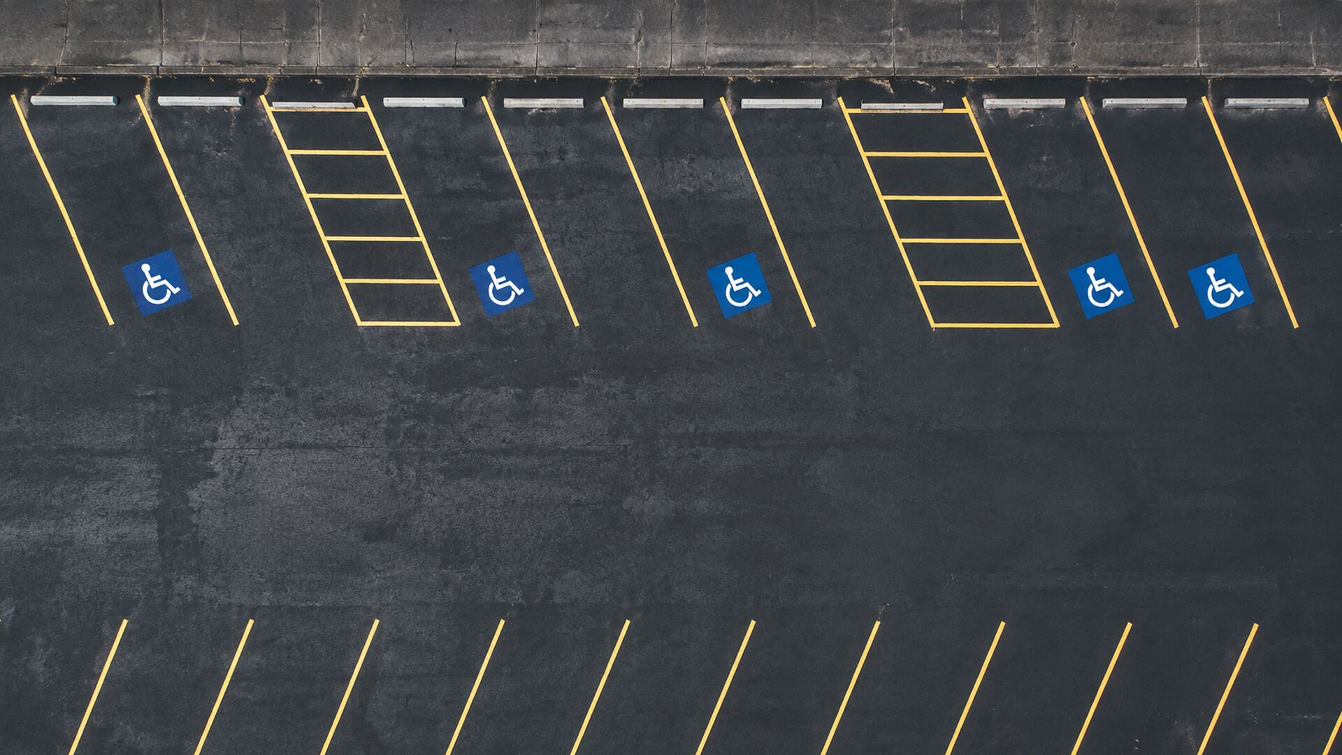 A freshly striped commercial parking lot with crisp white stall lines and a marked accessible space.